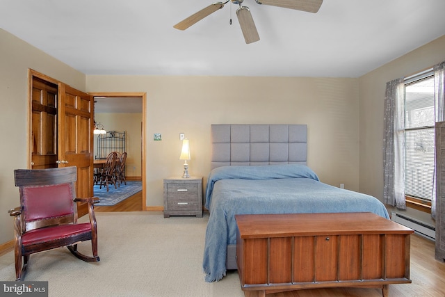 bedroom featuring a baseboard heating unit, a ceiling fan, and baseboards