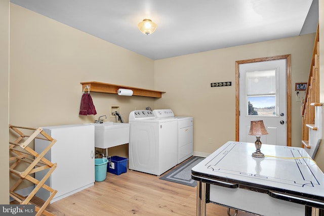 laundry area with light wood-style floors, laundry area, independent washer and dryer, and a sink