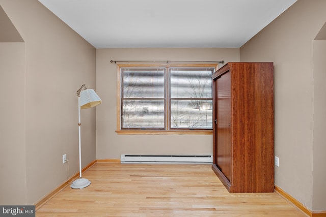 spare room with baseboards, baseboard heating, and wood finished floors