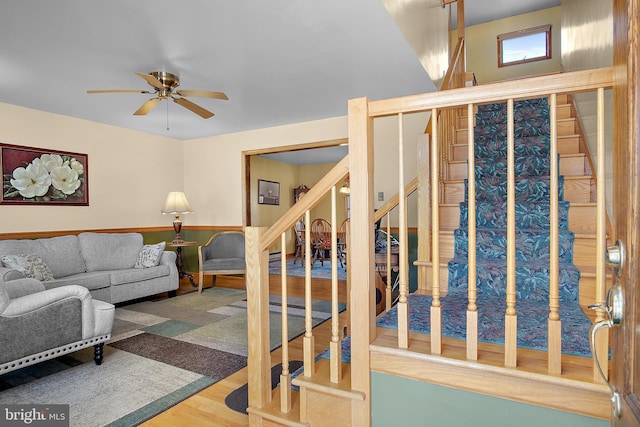 living room with stairway, wood finished floors, and a ceiling fan