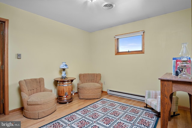 sitting room with baseboards, visible vents, baseboard heating, and wood finished floors