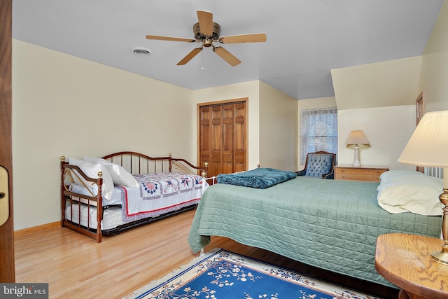 bedroom with wood finished floors, visible vents, baseboards, a ceiling fan, and a closet