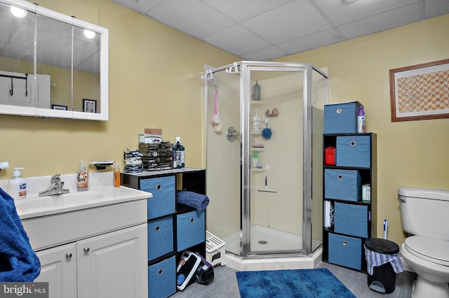 bathroom featuring a drop ceiling, a shower stall, toilet, and vanity