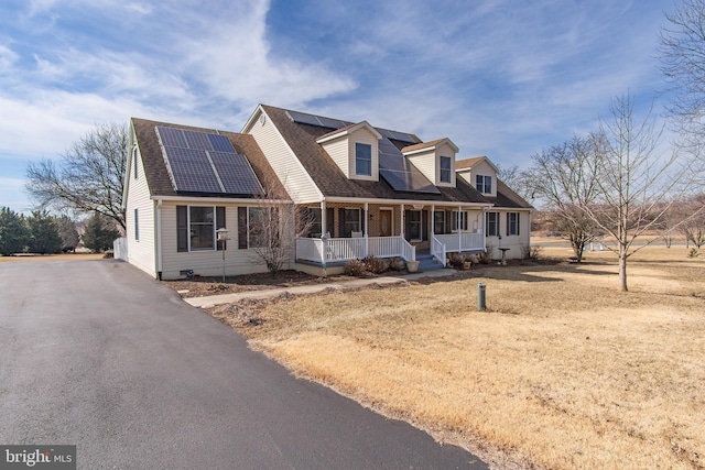 cape cod house with a porch, solar panels, roof with shingles, and aphalt driveway