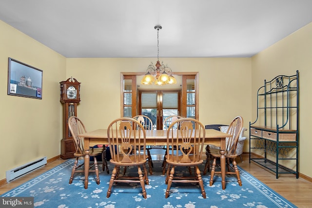 dining area featuring a baseboard heating unit, wood finished floors, baseboards, french doors, and an inviting chandelier