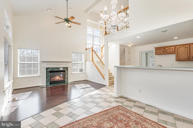 unfurnished living room featuring high vaulted ceiling, a high end fireplace, beam ceiling, and stairs