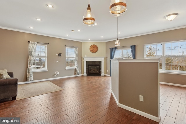 living area with baseboards, a glass covered fireplace, wood finished floors, crown molding, and recessed lighting