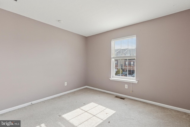 empty room featuring carpet floors, visible vents, and baseboards