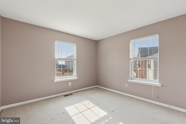 carpeted spare room with visible vents and baseboards