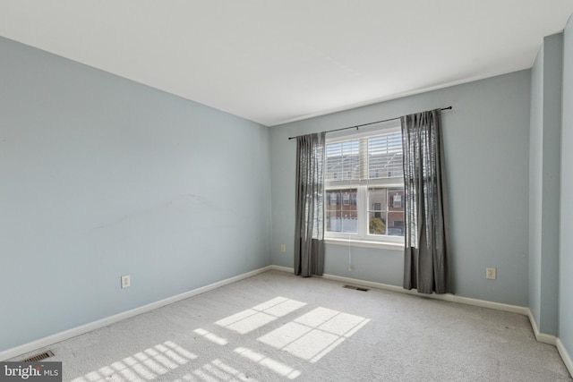 empty room featuring carpet floors, visible vents, and baseboards