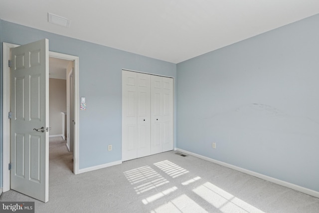 unfurnished bedroom with carpet floors, a closet, visible vents, and baseboards