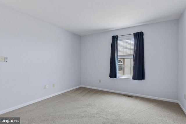 carpeted spare room featuring visible vents and baseboards