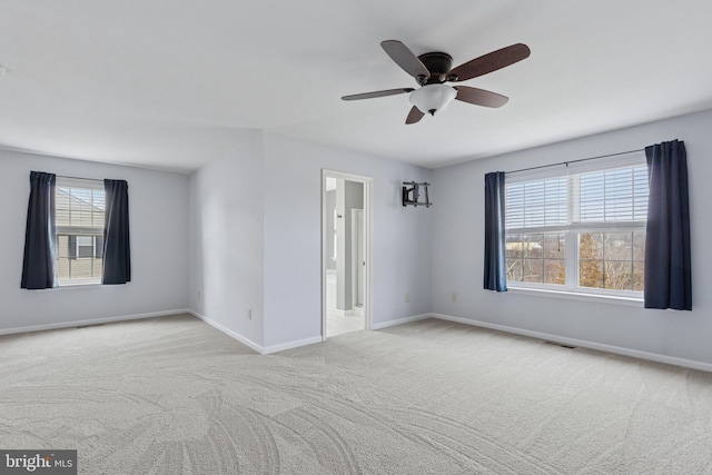 carpeted spare room with ceiling fan, visible vents, and baseboards