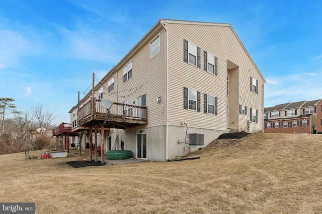 back of property with central AC unit, a deck, and a yard