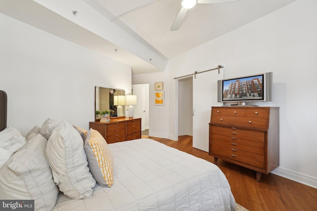 bedroom with a barn door, baseboards, vaulted ceiling, and wood finished floors