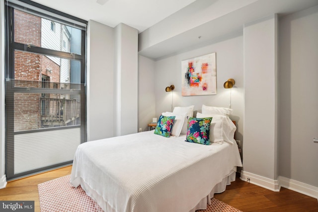 bedroom with floor to ceiling windows, wood finished floors, and baseboards