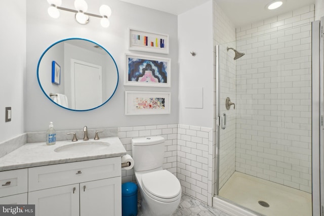 full bath with wainscoting, toilet, vanity, a shower stall, and tile walls