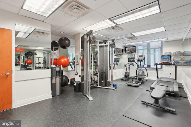 gym with a drop ceiling, visible vents, and baseboards