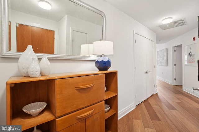 corridor with light wood finished floors, baseboards, and visible vents