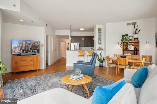 living area featuring wood finished floors, visible vents, and baseboards