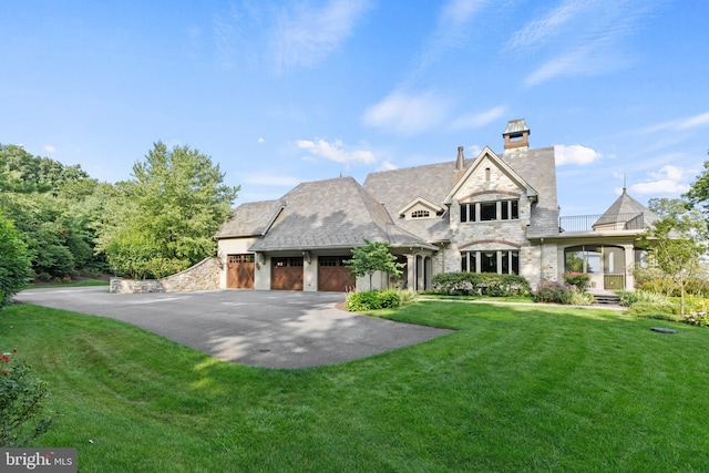 view of front facade with aphalt driveway, a front yard, stone siding, and an attached garage