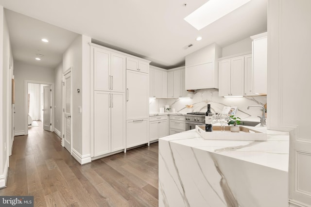 kitchen featuring recessed lighting, light stone countertops, light wood-style floors, and premium range hood