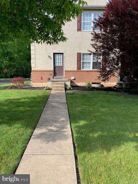 view of front of property featuring stucco siding, a front lawn, and brick siding