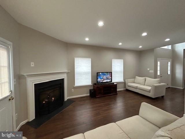 living area featuring a lit fireplace, baseboards, wood finished floors, and recessed lighting