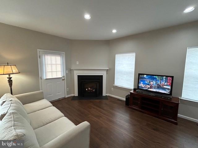 living area featuring a fireplace with flush hearth, baseboards, wood finished floors, and recessed lighting