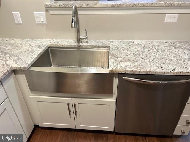 room details featuring dark wood-style floors, stainless steel dishwasher, light stone counters, and white cabinetry