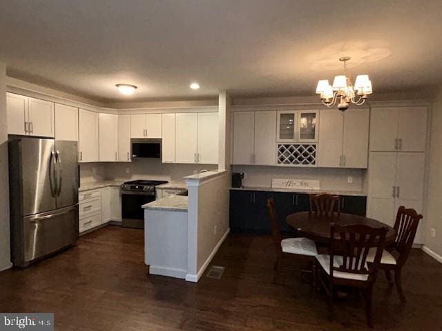 kitchen featuring appliances with stainless steel finishes, an inviting chandelier, dark wood finished floors, and white cabinets