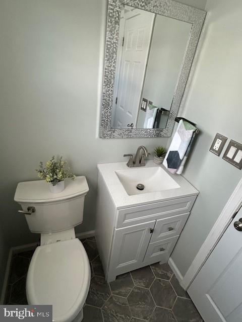 bathroom featuring baseboards, vanity, toilet, and tile patterned floors