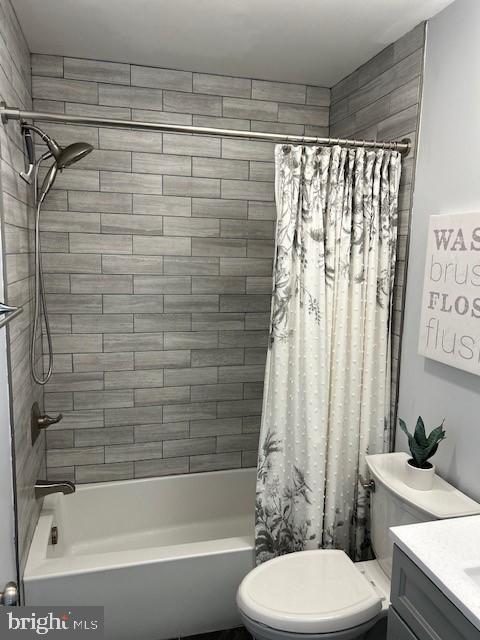 bathroom with toilet, shower / bath combo with shower curtain, and vanity