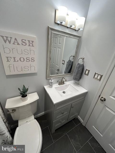 bathroom with toilet, baseboards, and vanity