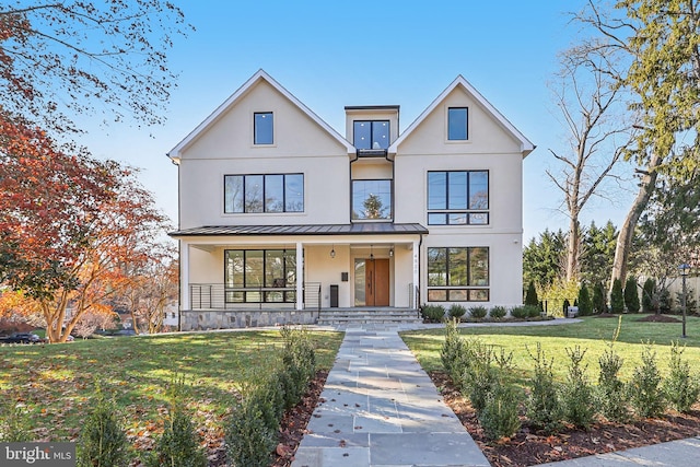 modern farmhouse style home featuring stucco siding, a porch, a standing seam roof, metal roof, and a front lawn