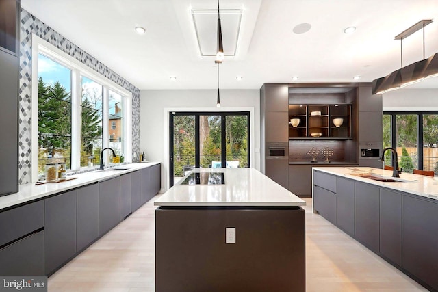 kitchen with modern cabinets, a kitchen island, a sink, and gray cabinetry