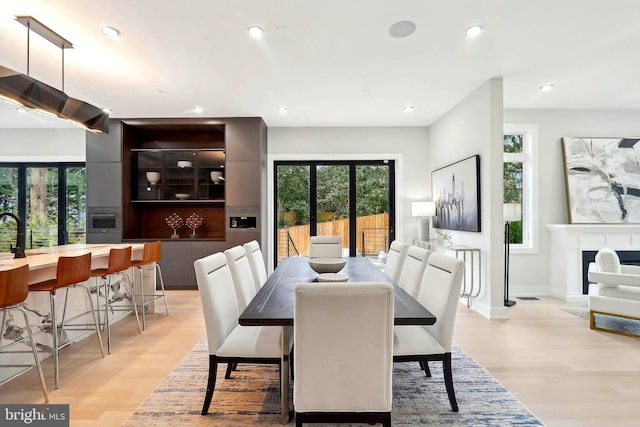 dining area with light wood finished floors, a fireplace, and recessed lighting