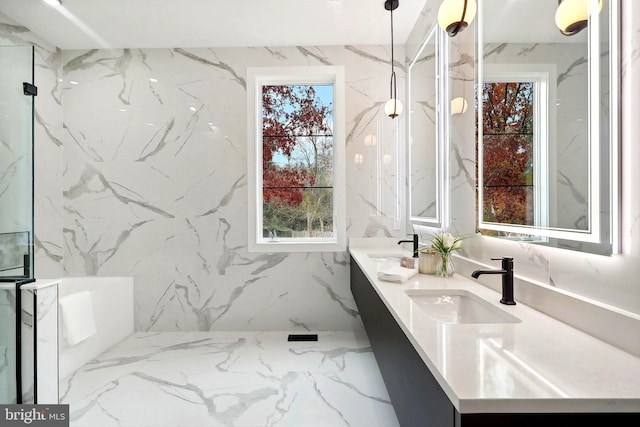 full bath featuring double vanity, stone wall, marble finish floor, and a sink