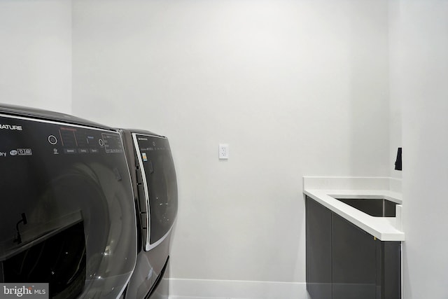 laundry room featuring cabinet space, baseboards, and separate washer and dryer