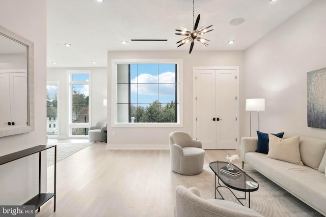 living room with recessed lighting, an inviting chandelier, baseboards, and wood finished floors