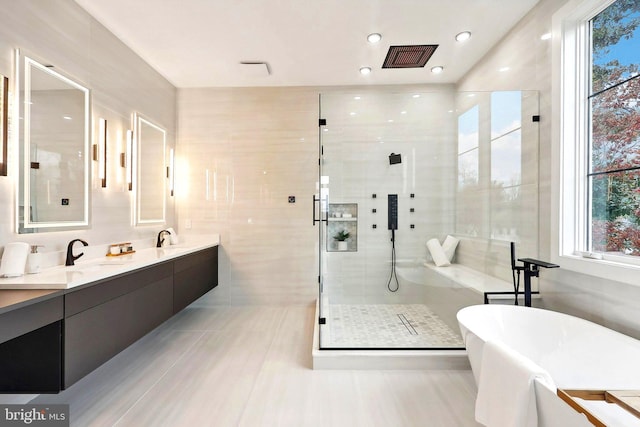 bathroom featuring a soaking tub, a shower stall, a wealth of natural light, and a sink