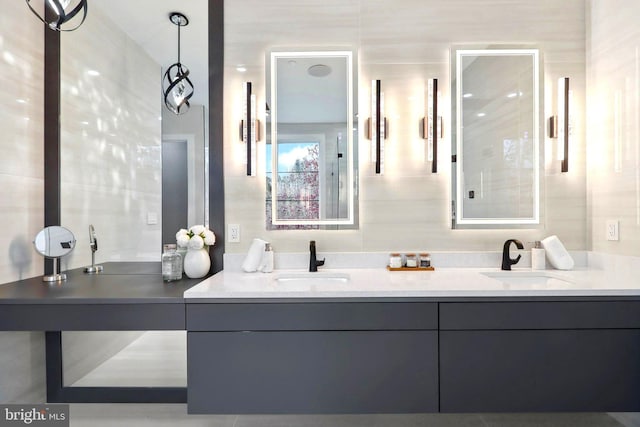 full bath with double vanity, a sink, and tile walls