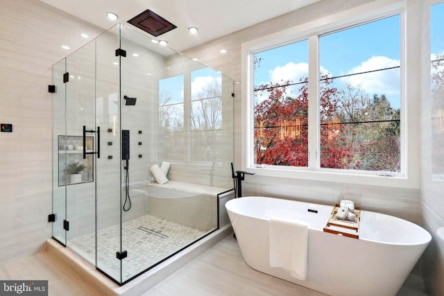 full bath featuring a soaking tub and a shower stall