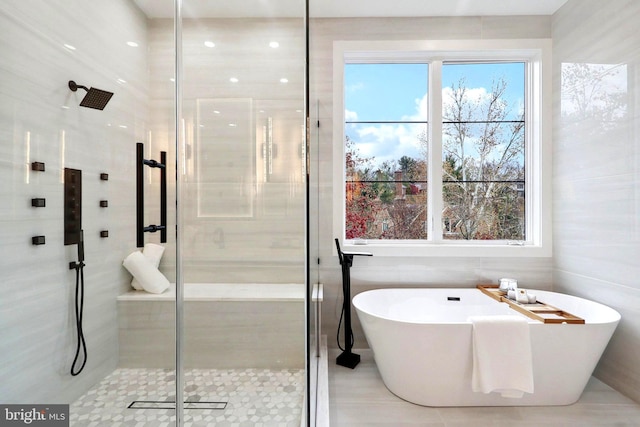 bathroom with a freestanding bath, a stall shower, and tile walls