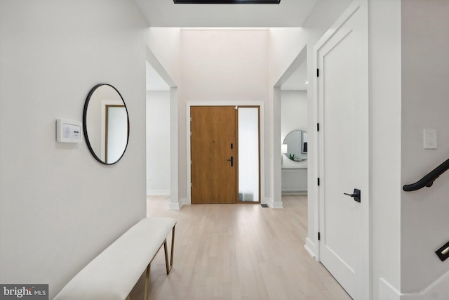 hallway featuring light wood finished floors and baseboards