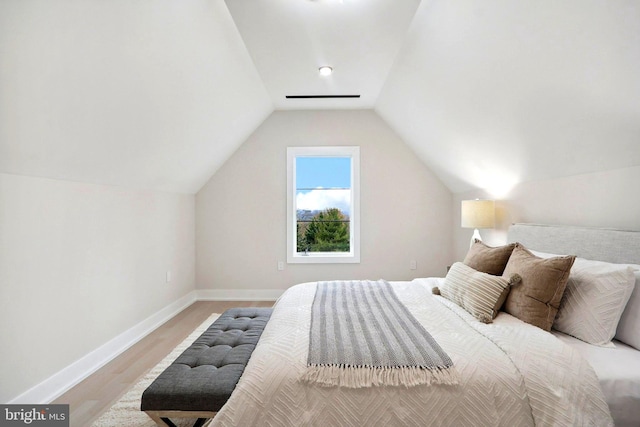 bedroom with vaulted ceiling, wood finished floors, and baseboards