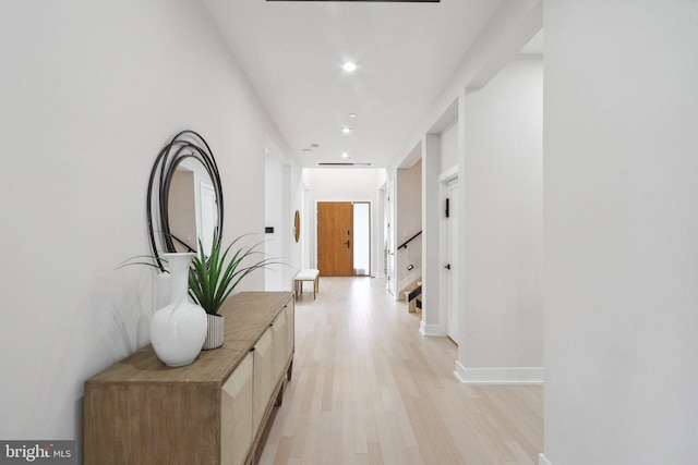 corridor featuring light wood finished floors, stairway, baseboards, and recessed lighting