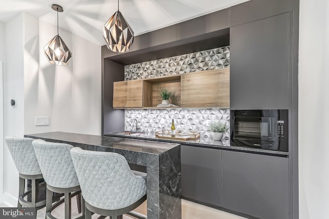 bar featuring tasteful backsplash, pendant lighting, and indoor wet bar