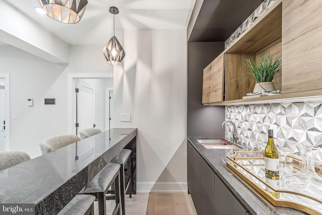 kitchen featuring light wood-style floors, tasteful backsplash, modern cabinets, and a sink