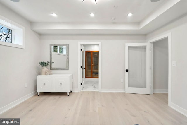 unfurnished bedroom featuring light wood finished floors, multiple windows, and baseboards